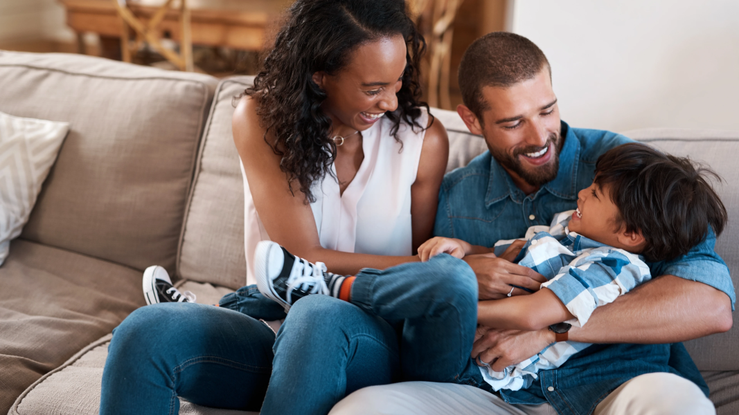 Family holding child on couch