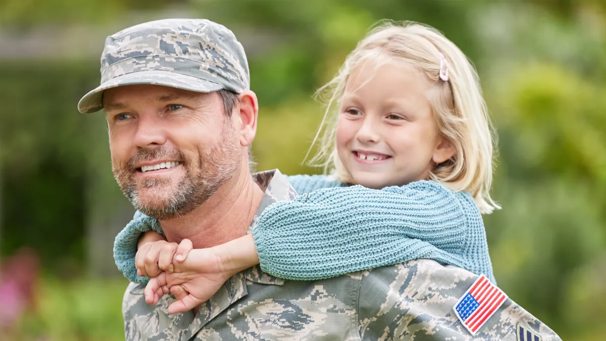 Veteran family holding house keys in front of a home