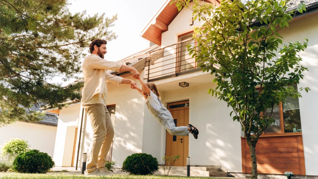 Dad swinging daughter outside of house