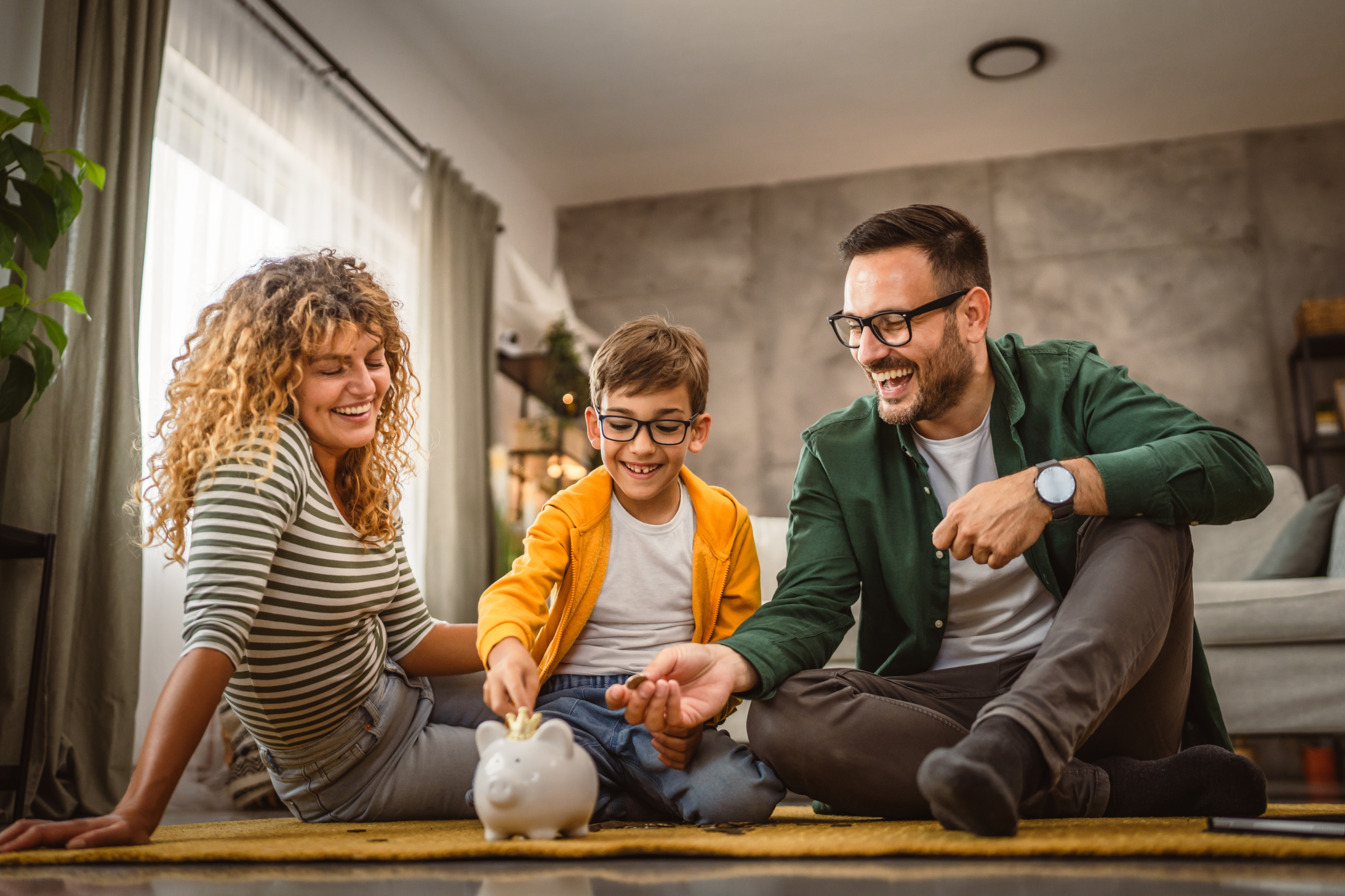 Happy family sitting next to a piggy bank on the floor of their new home