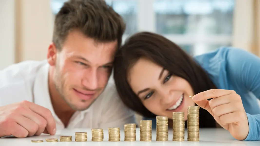 Smiling couple with stacks of coins
