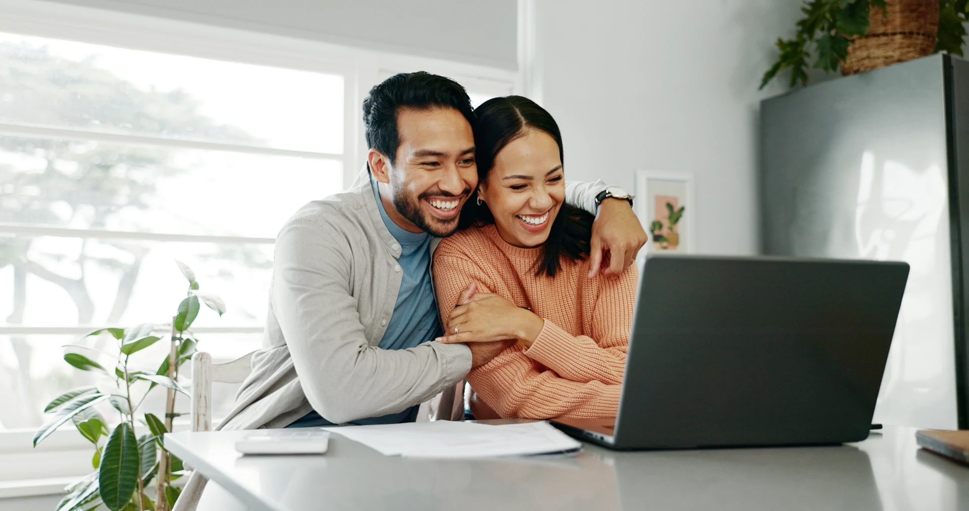 Happy Couple looking at a laptop computer in the kitchen