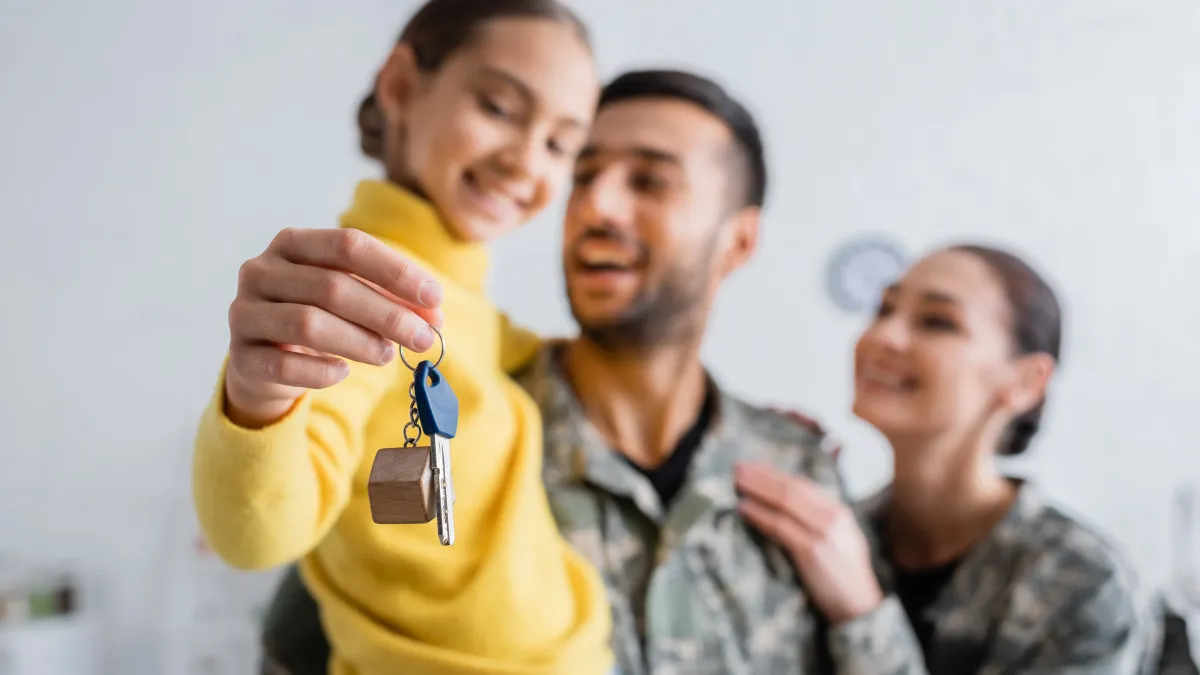 A veteran family holding house keys outside a home