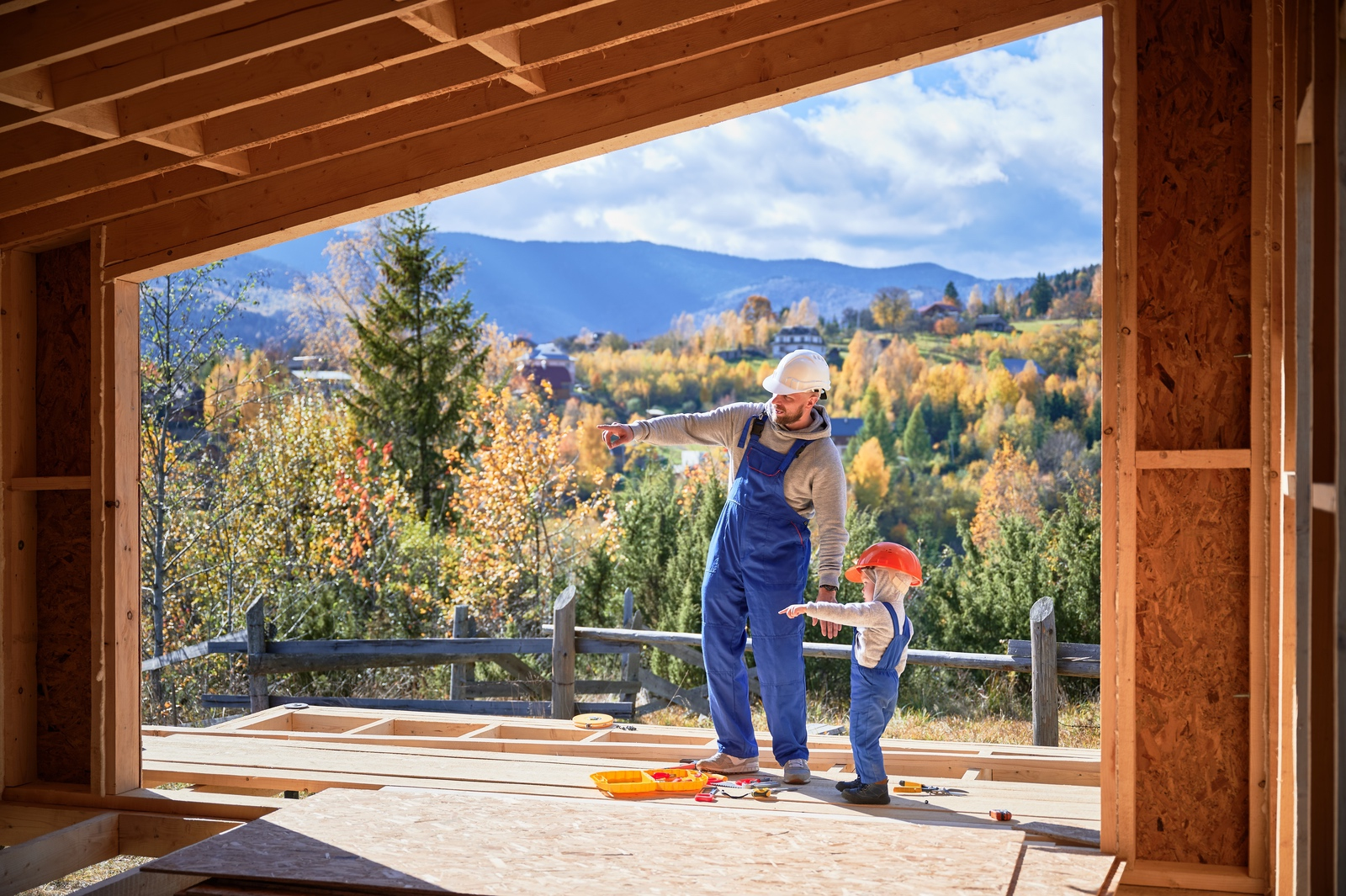 Father with toddler son building a wooden frame house