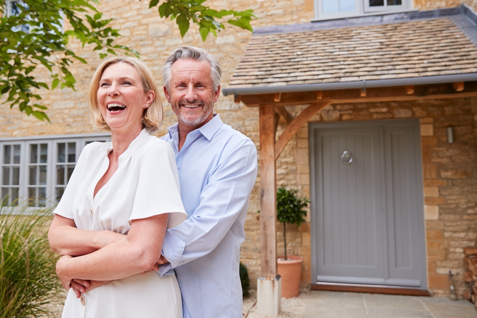 Senior couple standing outside their home with reverse mortgage