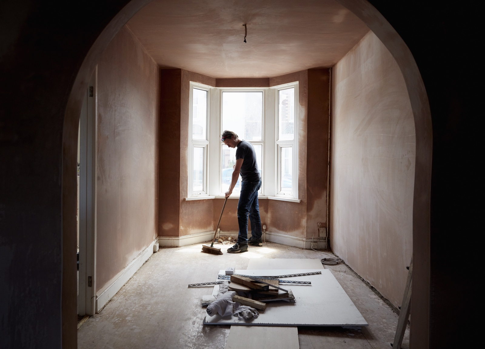 Builder sweeping and tidying up in a renovated room