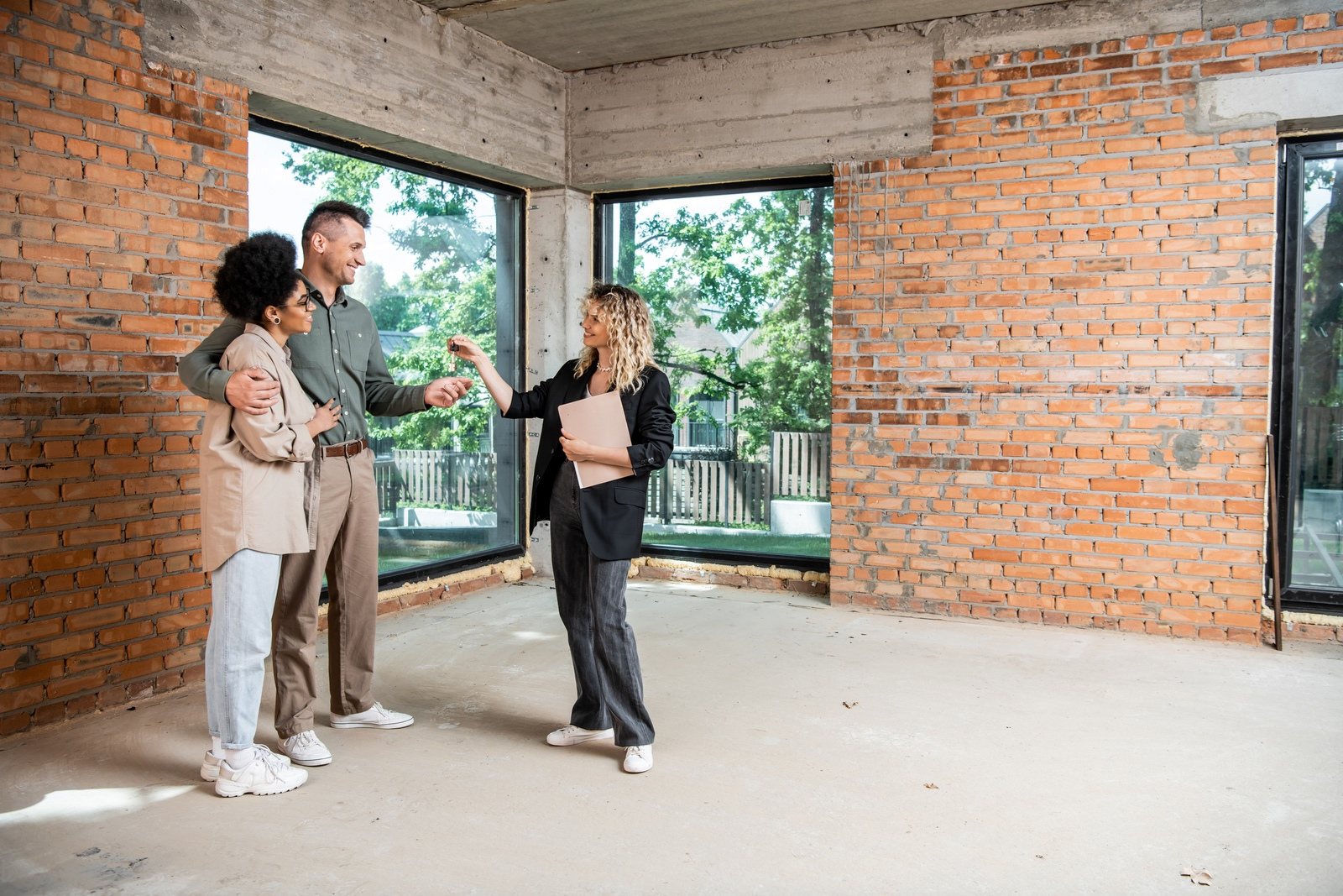 Real estate agent handing keys to a happy interracial couple