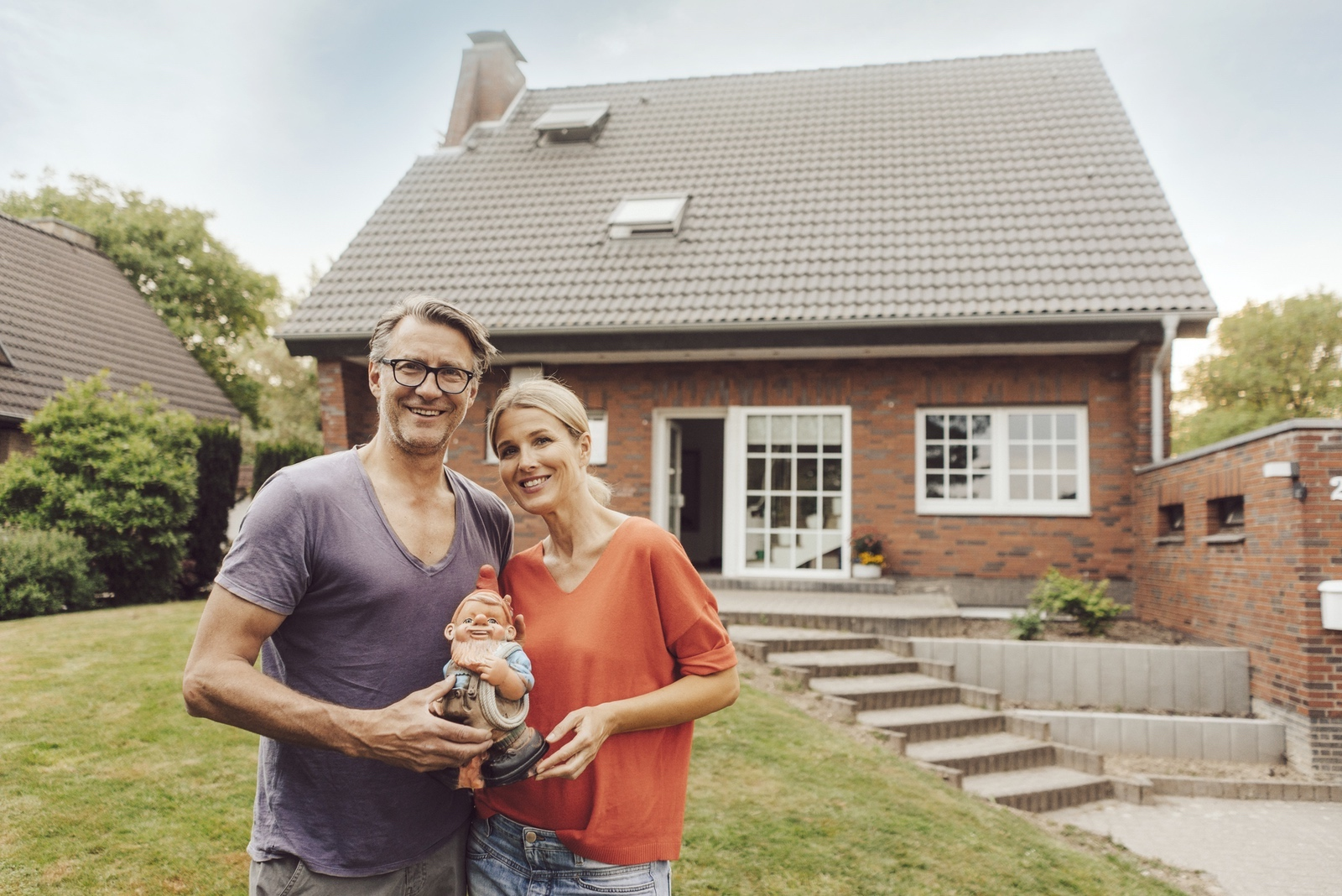 Happy senior couple standing in front of their new home