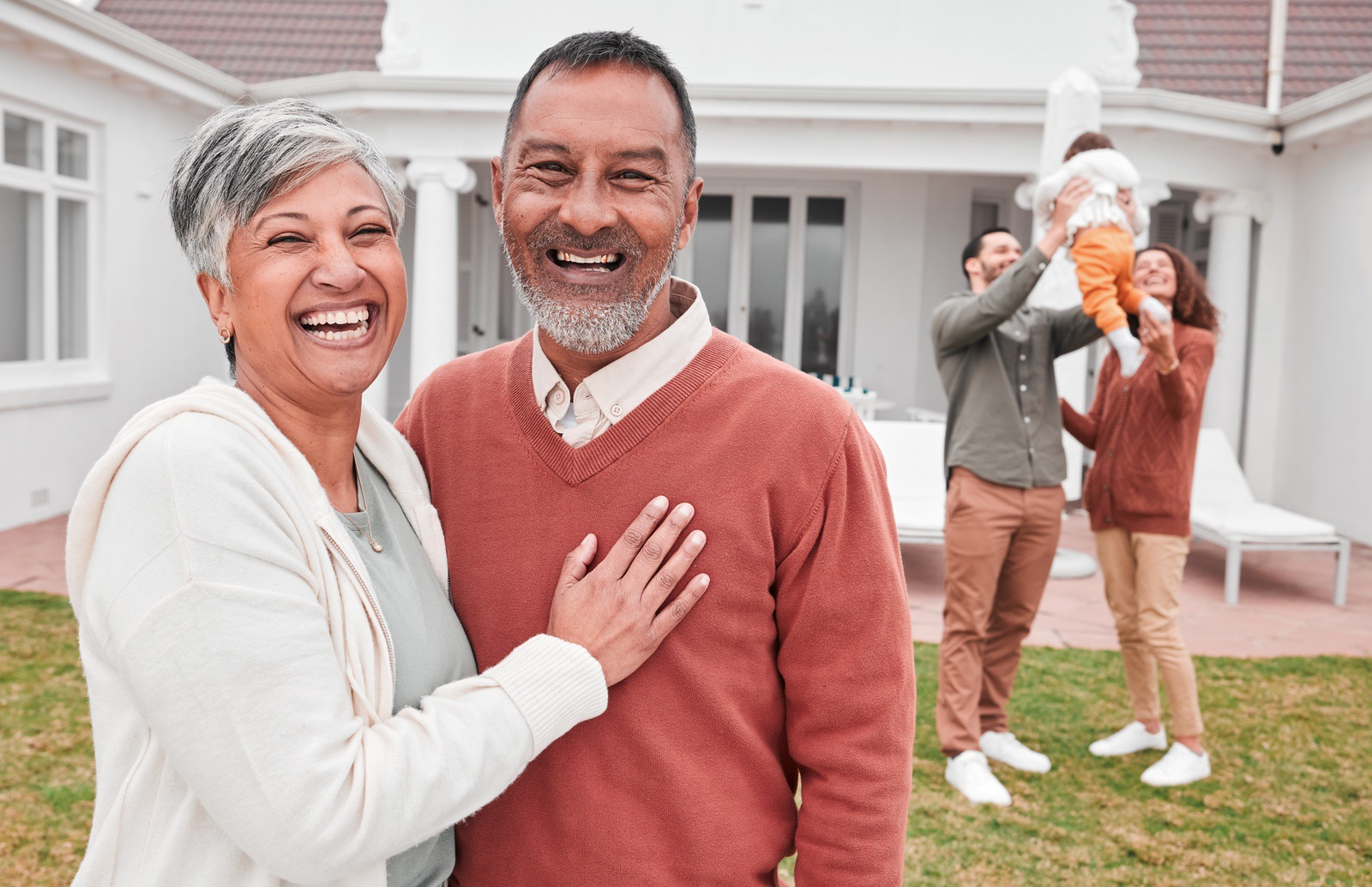 Senior couple standing outside their home, considering a reverse mortgage solution
